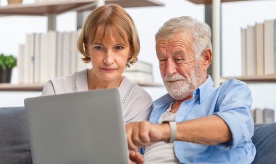 Two adults using a laptop together in the library